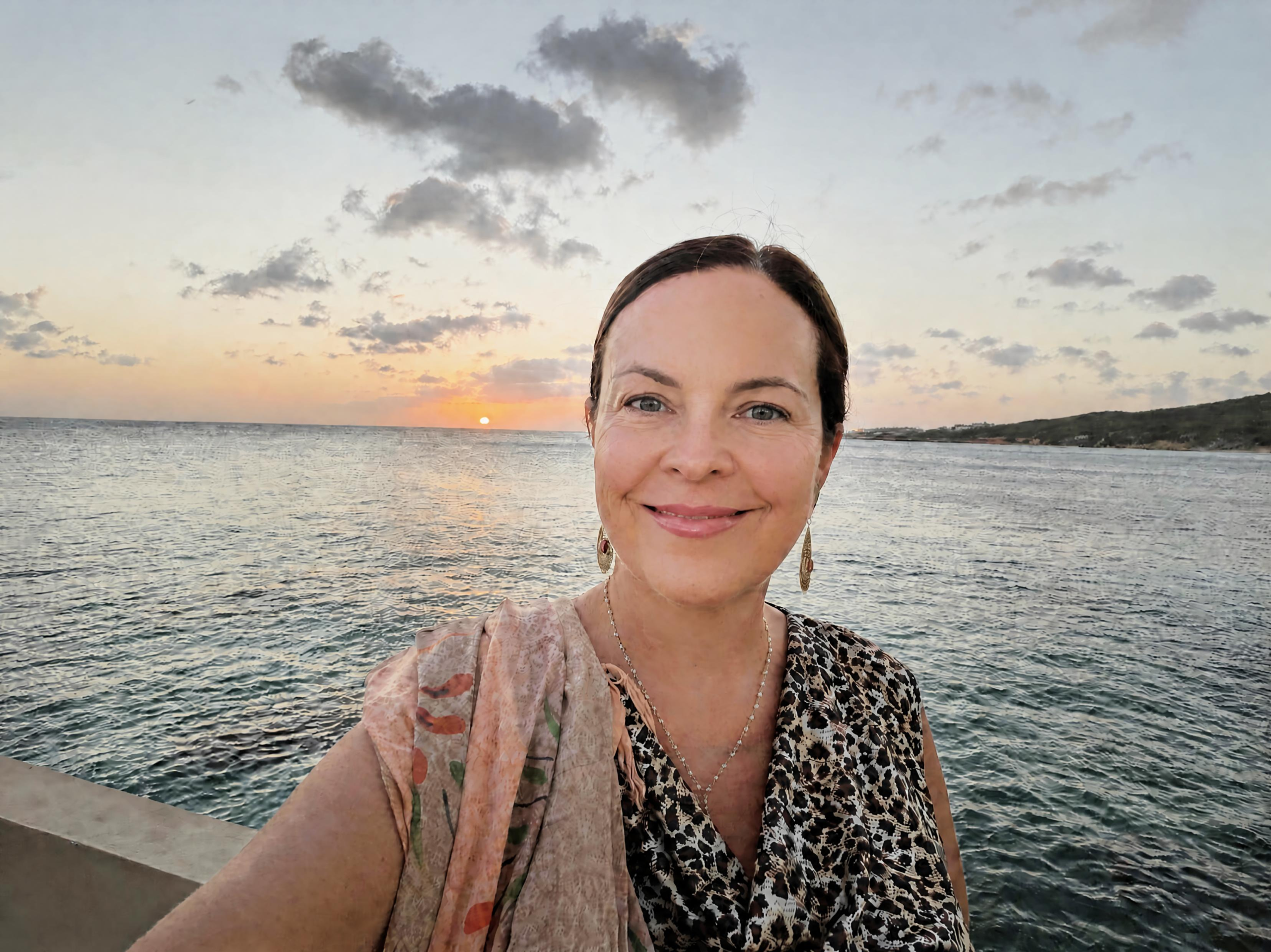 Jen in Curaçao at sunset, hand extended toward the camera